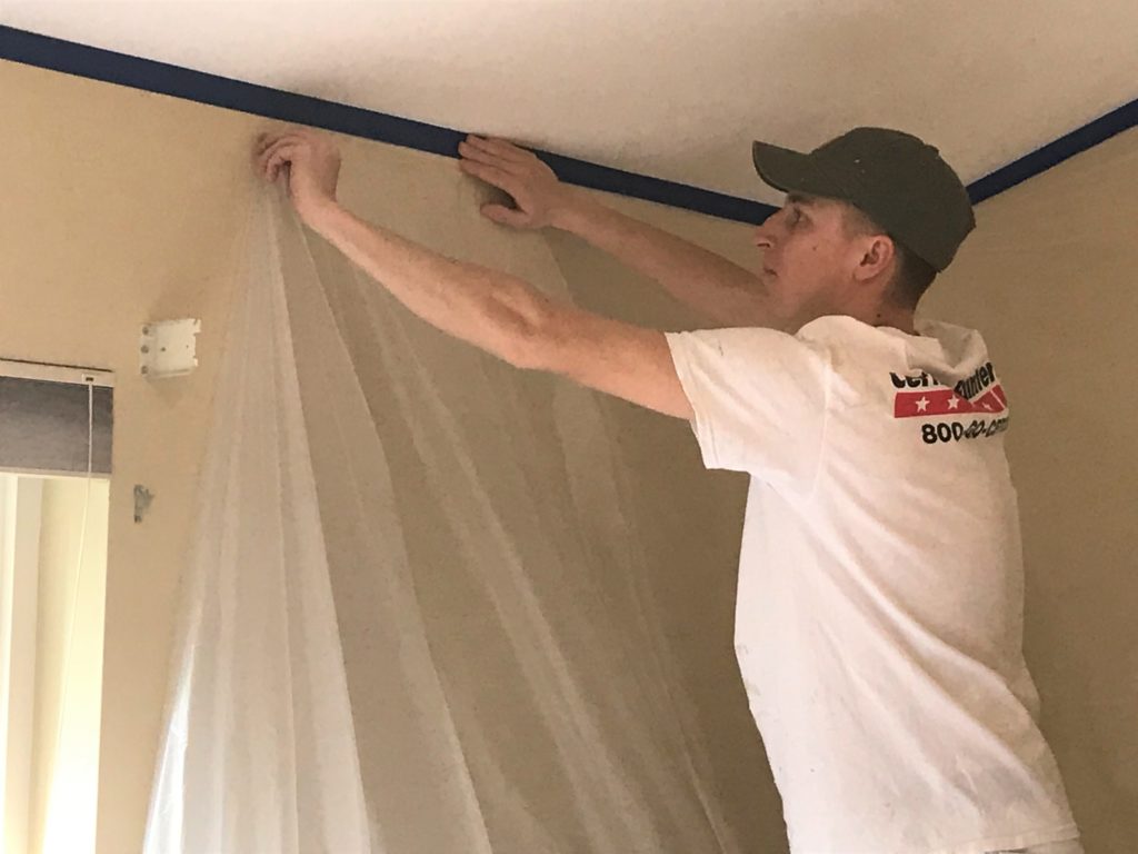 Professional painter hanging drop cloth and plastic