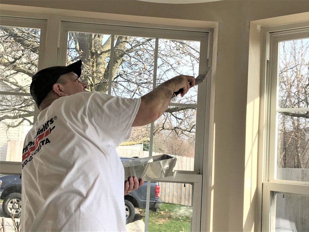 Professional painter patching window sill