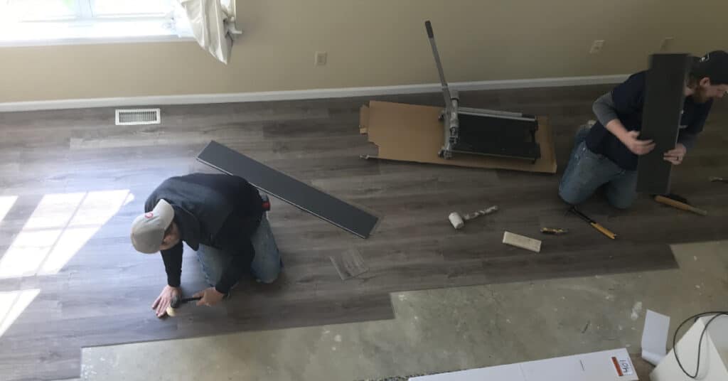 men installing vinyl flooring Tudor Floors & more Carpet One
